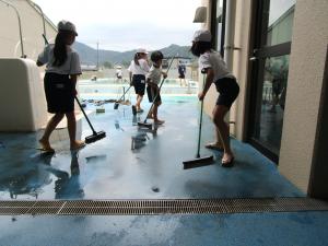 プールサイドをブラシでこする様子①